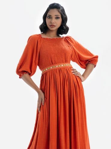 Printed maxi dress with smokes in viscose fabric. Boat neck with puff sleeves. Karchupi detailed belt on the waistline.
