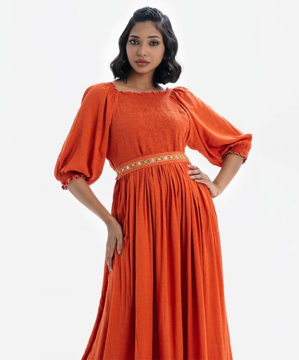 Printed maxi dress with smokes in viscose fabric. Boat neck with puff sleeves. Karchupi detailed belt on the waistline.