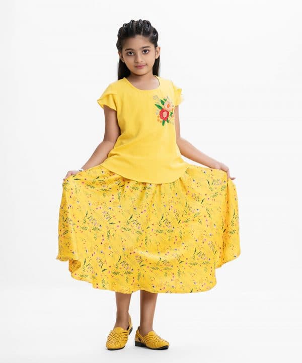Kid girl's woven set in georgette fabric with viscose inner. Cap sleeves, flower design karchupi at the front. Comes with a concealed elasticated with two pockets floral printed skirt.