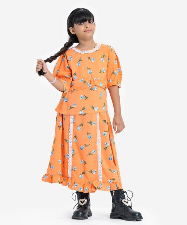 Kids girl woven set in georgette fabric. Round neck with lace work, short-sleeved. Attached belt at the waistline and a skirt with frill trims at the hemline and lace at the front.