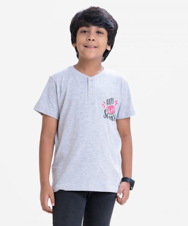 Kid boys henley t-shirt in cotton single jersey fabric. Round neck with front button fastening and short sleeves with a chest print.